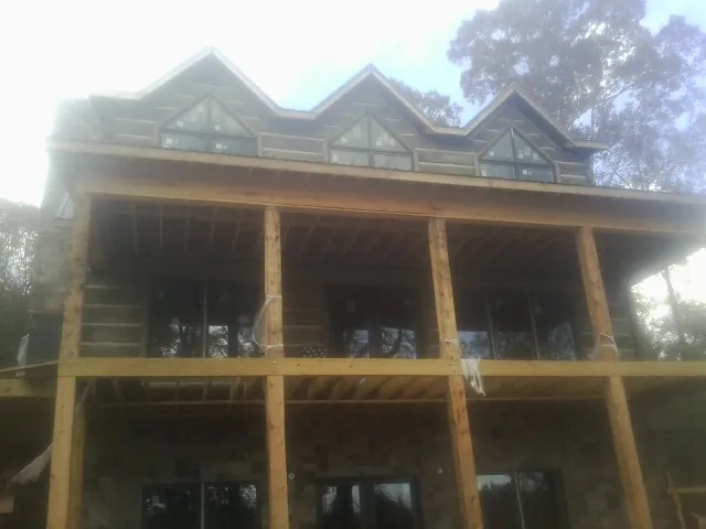 Dormers and porch framing on a large log home under construction — Roof Coating work by our crew in Mound City