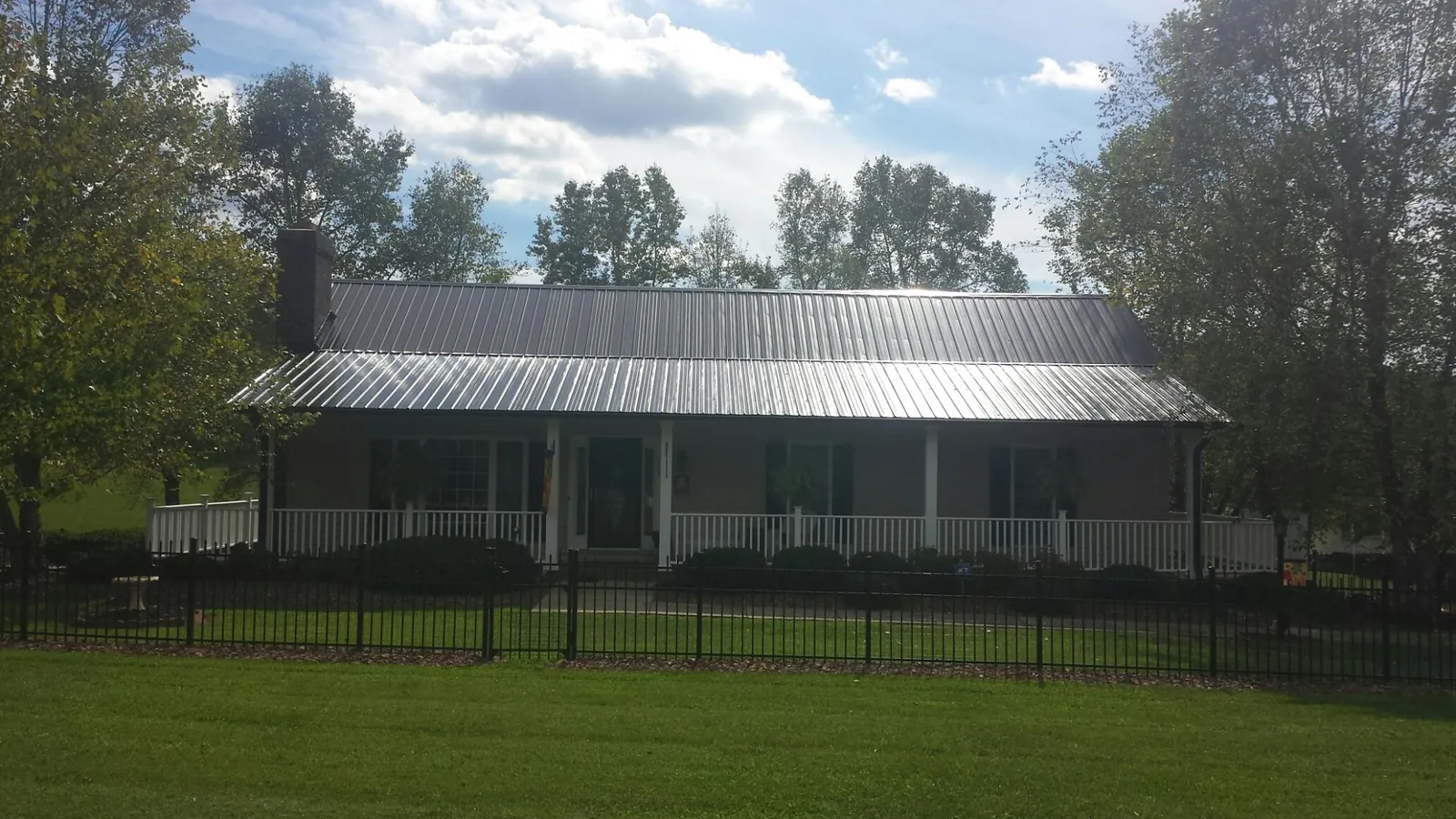 Gray metal roof on a brick ranch with a full width front porch — Gutter Guard Installation work by our crew in Mound City