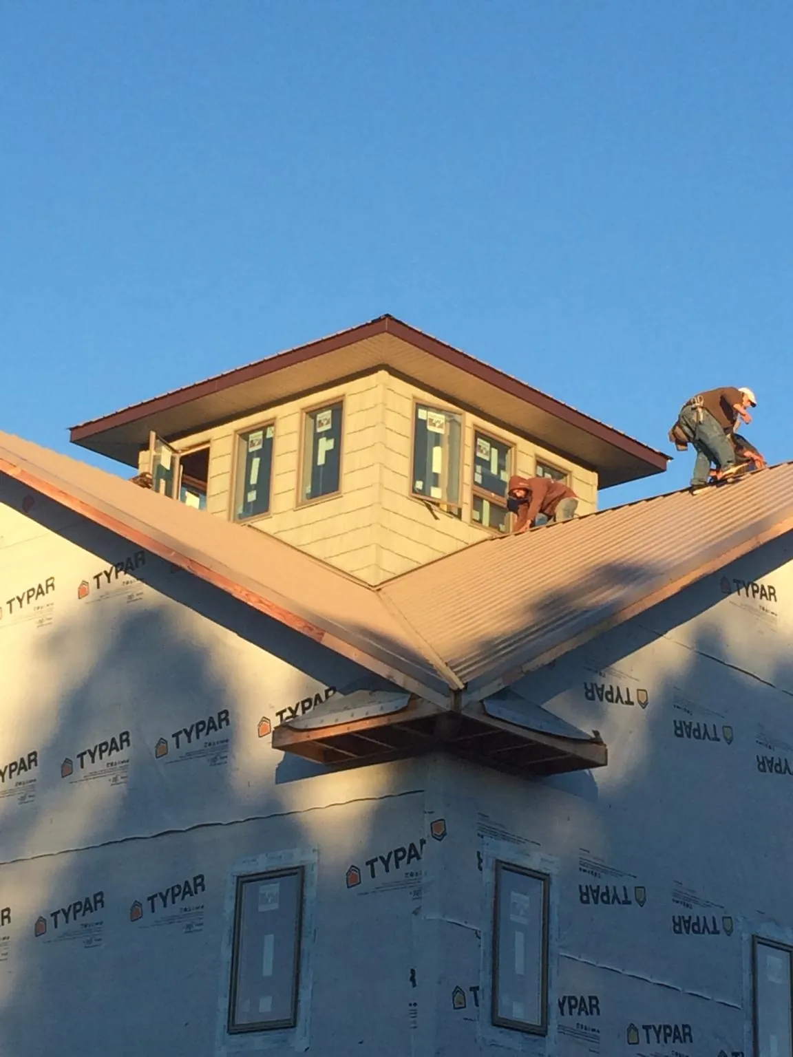 Roofers working around a rooftop cupola on a new metal roof at sunset — Roof Waterproofing in Mound City by Roofing Brothers